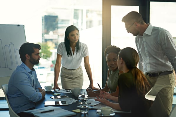 women_speaking_to_coworkers_sitting_at_a_table